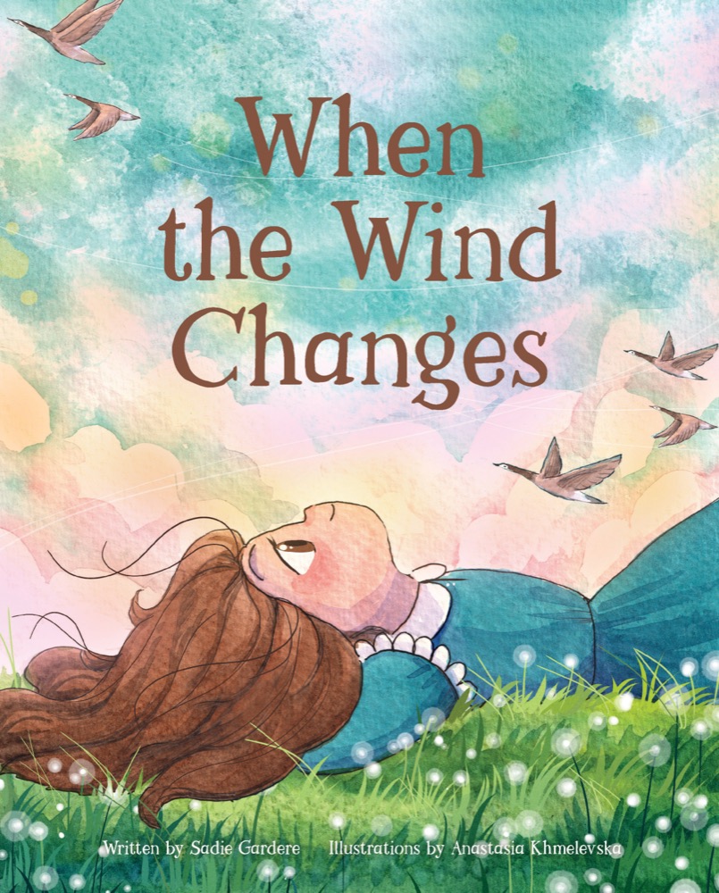 Cover of When the Wind Changes by Sadie Gardere: a child lying in the grass, looking up at a wide watercolor sky as geese fly overhead